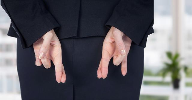 This image shows a businessperson in business attire with fingers crossed behind their back, signaling dishonesty or hope. Suitable for topics on business ethics, corporate dishonesty, strategic decisions, or trust issues in the workplace. Ideal for use in articles, blogs, and presentations discussing these themes.