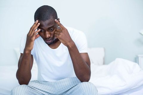 Man Sitting on Bed, Focused and Contemplative in Casual Home Setting