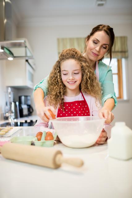 Mother and daughter bonding while baking in the kitchen. Perfect for themes related to family, cooking, parenting, and home life. Can be used in advertisements, blogs, and articles about family activities, recipes, and childhood education.