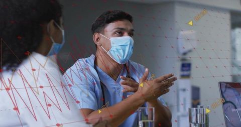 Masked clinician discussing patient data with team during hospital briefing