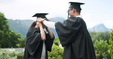 Graduating couple smiling outdoors in caps and gowns