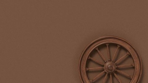 Vintage wooden wagon wheel against brown wall with copy space