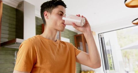 Young Man Drinking Fresh Fruit Smoothie in Modern Kitchen