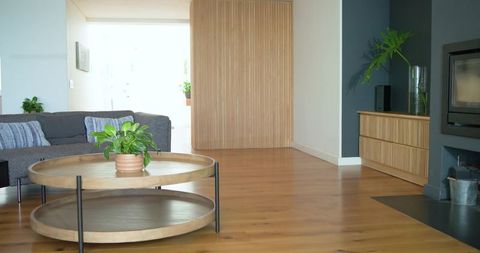 Modern minimal living room featuring round wooden coffee table, oak floor, natural light