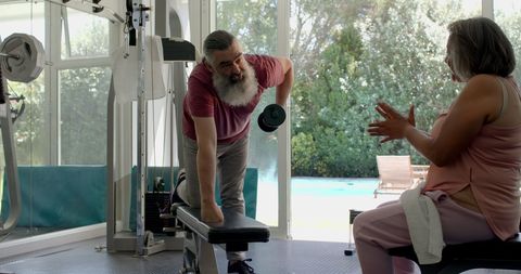 Senior man lifting weights at home with encouragement