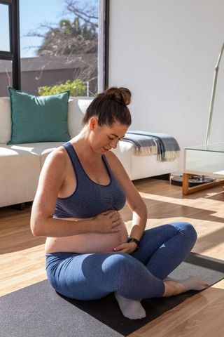 Pregnant woman meditating comfortably at home