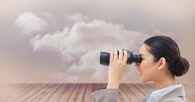 Businesswoman in formal attire using binoculars, looking at a cloudy sky. Useful for concepts related to business vision, strategy, searching for opportunities, exploration, professional growth, and future planning.