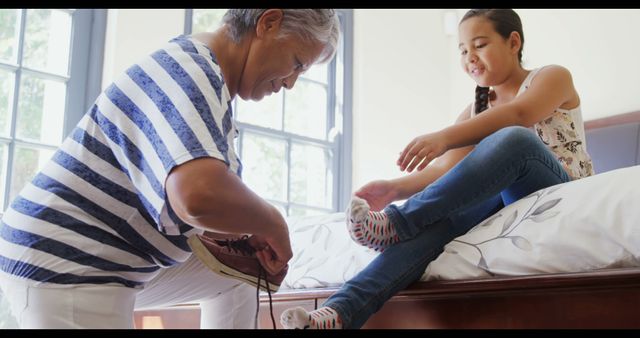 Grandparent Helping Grandchild Put On Shoes In Sunlit Room - Download Free Stock Images Pikwizard.com