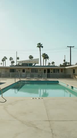 Vertical Cinematic: Rippling Retro Motel Pool and Swaying Palm Trees under Sunlit Blue Sky