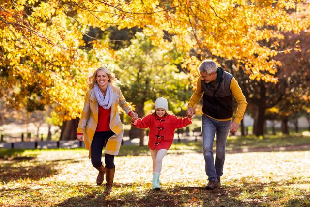 Joyful family walking against trees at park during autumn