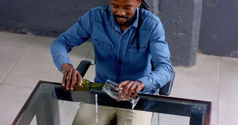Man in Denim Shirt Relaxing at Modern Office with Beverage