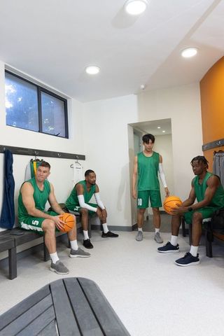 Multiracial basketball team planning game strategy in locker room before tip-off