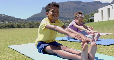 Children Stretching Outdoors on Yoga Mats in School Field
