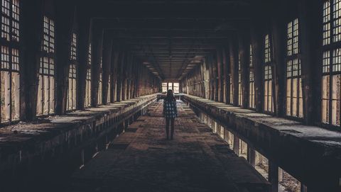 Woman exploring eerie abandoned industrial building