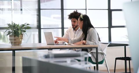 Collaborative colleagues working on laptop in modern office