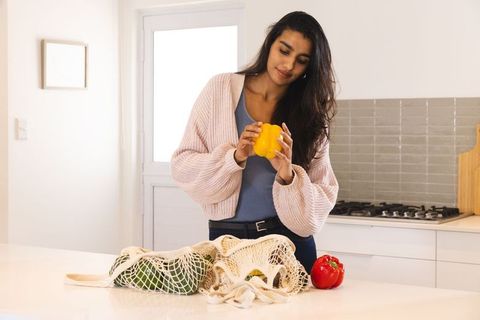 Woman inspecting yellow bell pepper in modern kitchen