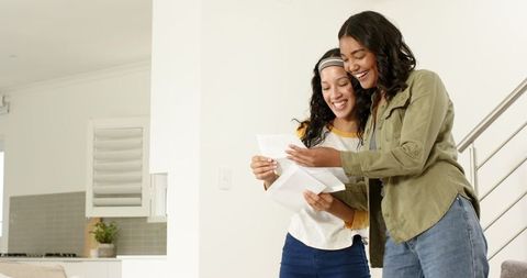 Mother and Daughter Laughing Reading Letters Together at Home