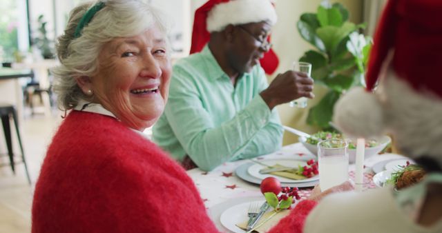 Happy caucasian senior woman celebrating meal with friends at christmas time. christmas festivities, celebrating at home with friends.