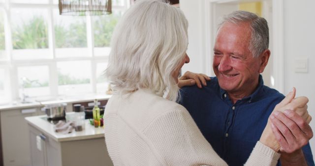Happy caucasian senior couple having fun dancing together in kitchen. Romance, relaxation, togetherness, retirement and senior lifestyle, unaltered.