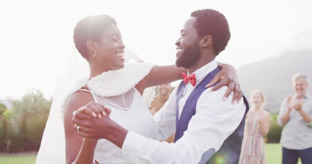 Happy african american couple holding hands and dancing during wedding. Wedding day, friendship, inclusivity and lifestyle concept.
