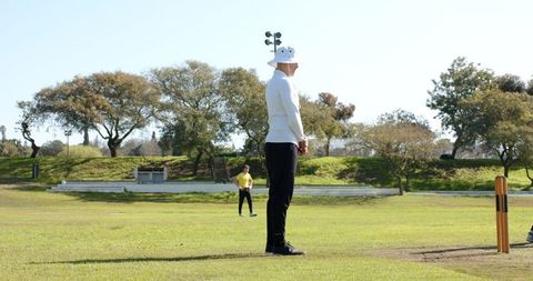 Cricket umpire standing on green field under clear sky in sunny weather