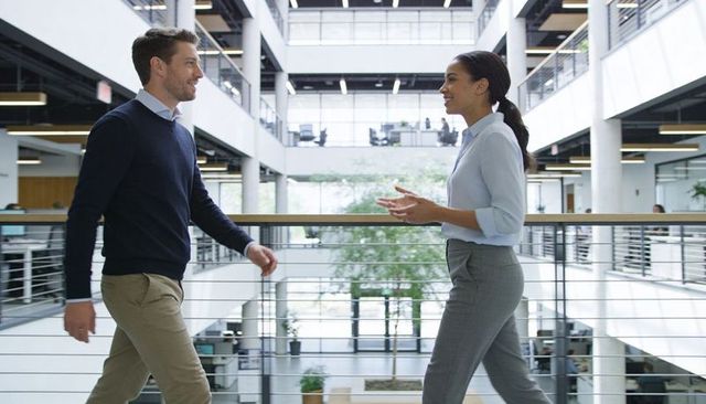 Colleagues walking and talking in modern open-plan office atrium conveying collaboration