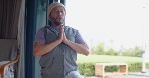 Man Meditating at Home Near Glass Door Embracing Wellness
