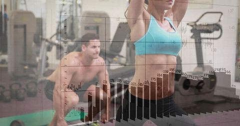 Female athlete stretching core while partner lifting kettlebell with fitness data overlay