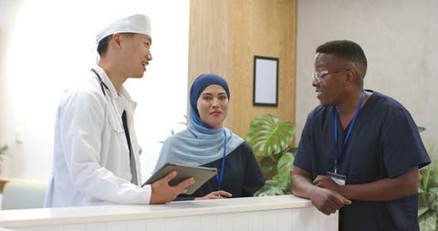 Multicultural medical team consulting at clinic reception desk with tablet and stethoscope