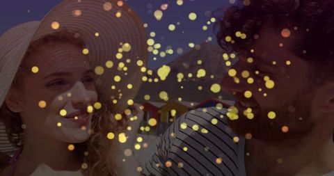Sunlit beach couple wearing straw hat and striped shirt with golden bokeh lights