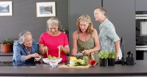 Joyful Diverse Seniors Group Preparing Salad Together in Modern Kitchen