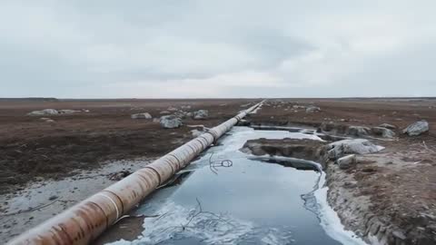 Aerial View of Rusty Pipeline Traversing Frozen Tundra