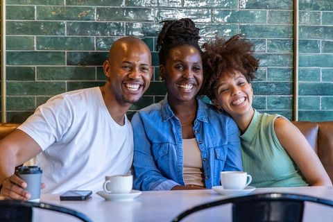Smiling african american friends sharing coffee and laughter in cozy café
