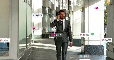 Businessman walking in sunlit glass arcade using smartphone with floating social icons