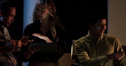 Diverse colleagues collaborating with technology in late-night office session