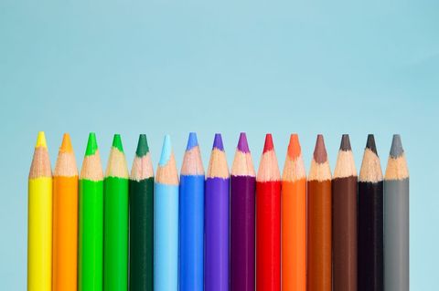 Colorful pencils lining up in rainbow order on pastel blue background