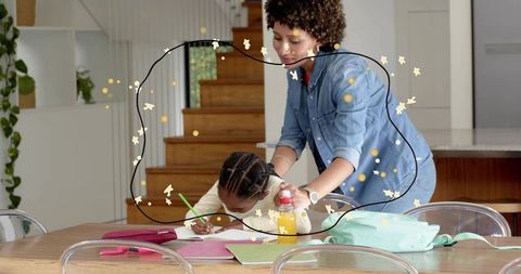 Caregiver guiding child with homework at kitchen table during home learning and study time