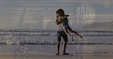 Father lifting child in joyful embrace on sunlit beach shoreline during golden hour