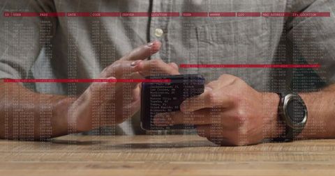 Mid-adult man tapping smartphone on wooden desk while data overlay displaying analytics