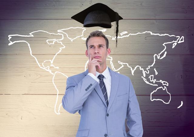 Thoughtful businessman with mortarboard above head and world map against wooden background