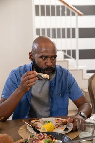 Mature man enjoying grilled meal at home dining table