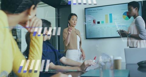 Asian woman presenting online sales analytics on screen in modern corporate meeting