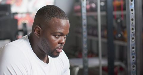 Focused african man resting after intense weightlifting session in gym