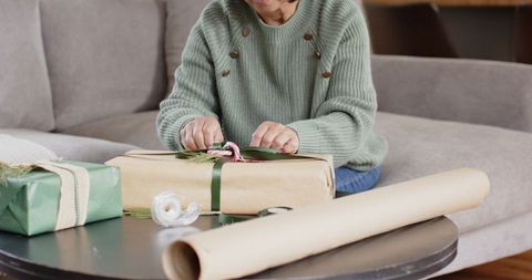 Senior Woman Crafting Wrapping Paper Gift on Table at Home