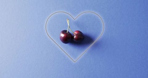 Fresh Cherries in Neon Heart Over Blue Background