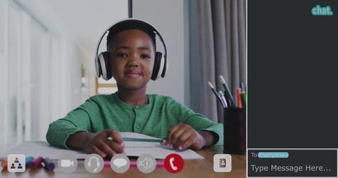 Elementary boy wearing headphones studying and focusing during remote learning at desk