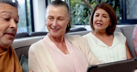 Senior Friends Gathering, Engaged with Tablet in Cozy Living Room