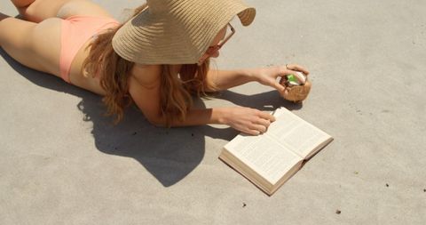 Woman Relaxing on Beach Reading Book and Drinking Coconut Water