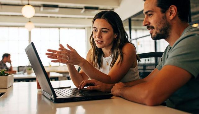 Young professionals collaborating on laptop in modern open-plan coworking workspace