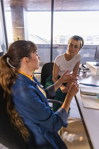 Female Colleagues Engaged in Discussion at Office Lab with Microscope